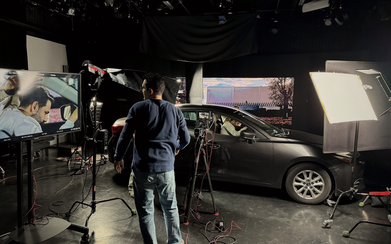 Behind-the-scenes film production stage with camera, lighting and vehicle rig